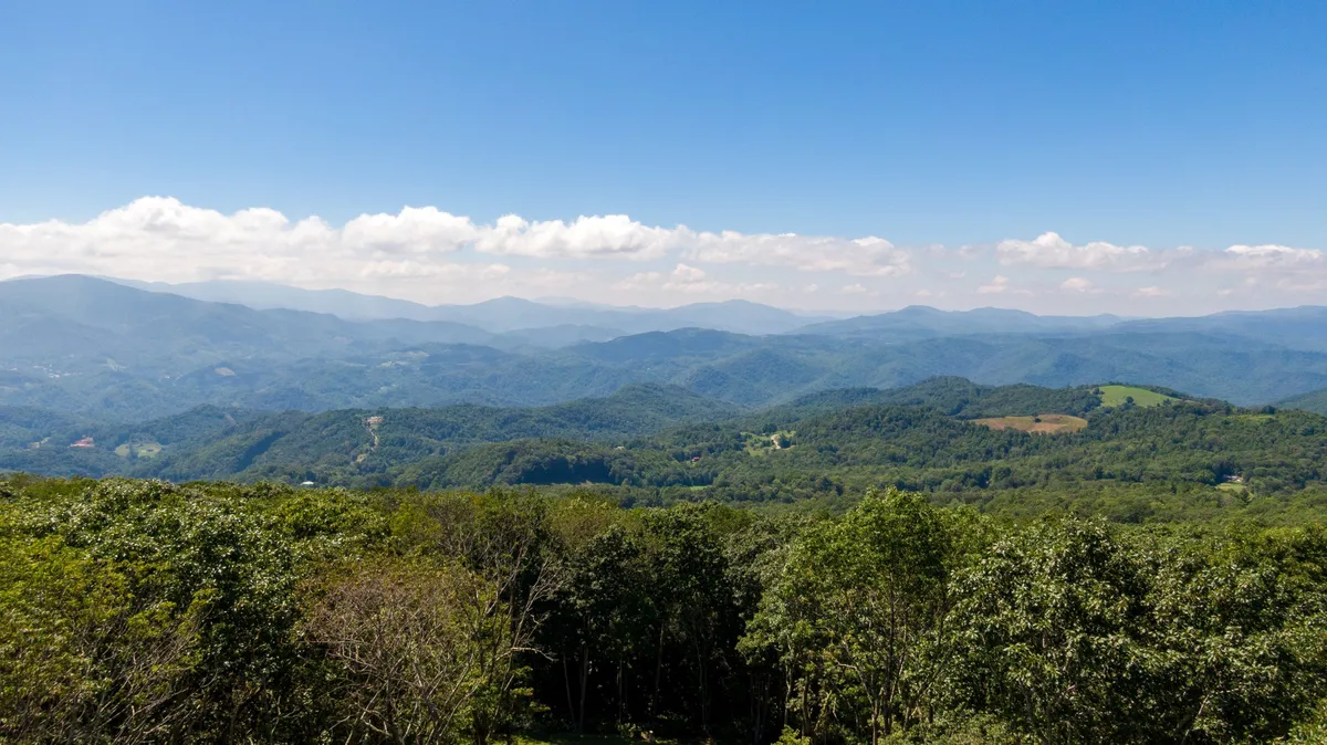A panoramic view of the surrounding mountain range, valleys, and treetops under a wide, open sky. The image embodies the breathtaking scenery families can experience while hiking, exploring trails, or visiting nearby natural attractions.